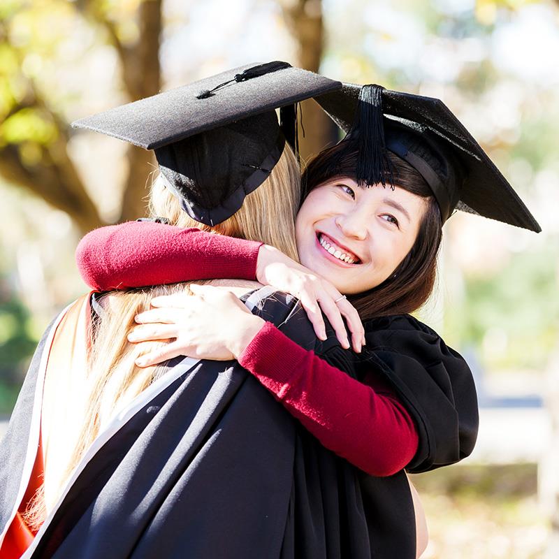 Female university graduates hugging and smiling