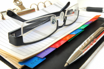 a pair of glasses sitting on an open day planner with the alphabetised tabs in the foreground
