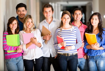 A group of happy students standing together, holding their notebooks