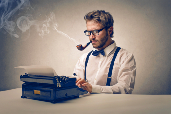 A man with good-looking clothes and eye-glasses smoking a pipe and typing something on a typewriter