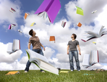 Two male students with books flying around them